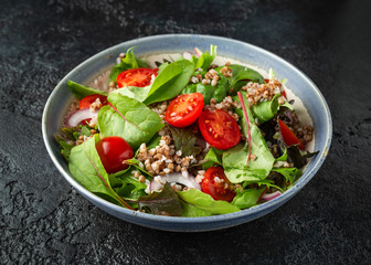 Buckwheat salad with cherry tomatoes, red onion and green vegetables. Healthy diet food