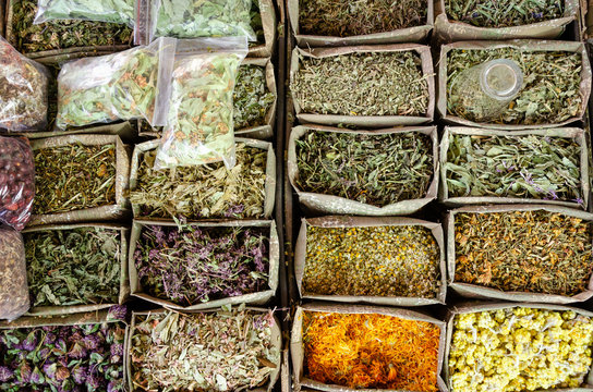 Containers with dried medicinal herbs for sale on the market. Healing herbs. Alternative medicine concept
