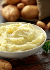 Mashed potatoes in white bowl on wooden rustic table. Healthy food