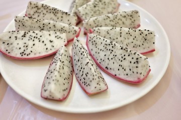 A group of slice dragon fruit in a plate on white dinning table
