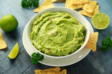 Bowl of fresh Guacamole with nachos chips and herbs. Healthy Vegan, Vegetables food. - obrazy, fototapety, plakaty