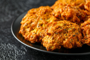 Indian takeaway food, spicy onion bhajis on black plate