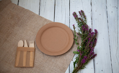 ecological disposable tableware paper cardboard empty on a wooden white table with yellow flowers