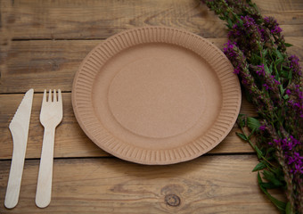 vintage wooden empty table with purple flowers with disposable tableware