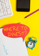 Text sign showing Where To Invest question. Business photo showcasing asking about actions or process of making more money Empty red bubble paper on the table with pc keyboard