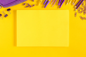 Back to school concept. Purple school supplies on yellow paper background. Flat lay, top view, copy space