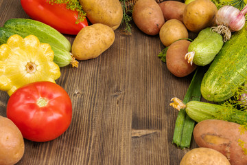 Red, yellow and green vegetables lie on a dark gray wooden surface, in the center there is an empty place, side view from above