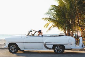 Happy young woman and retro convertible car - obrazy, fototapety, plakaty