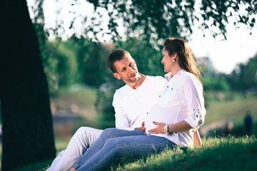 future parents sitting on the grass in the Park on a Sunny day.