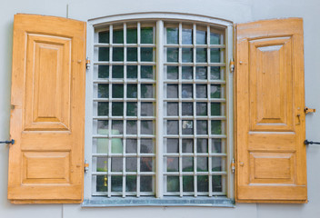 Simple window with yellow shutters on the gray wall