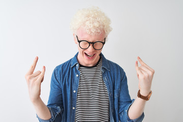Young albino blond man wearing denim shirt and glasses over isolated white background shouting with...