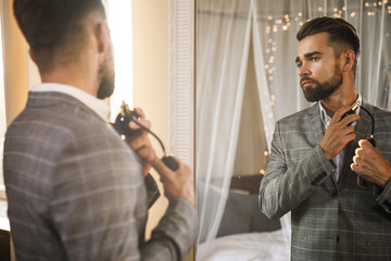 Handsome bearded man is using atomizer nozzle with perfume