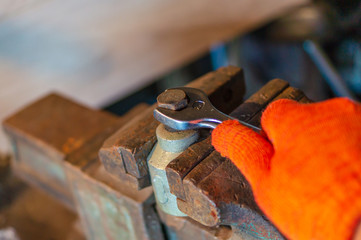 Worker hand tightening or loosening a nut of a bolt with a wrench.