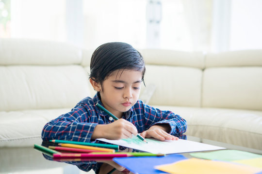 Little child drawing on a paper at home