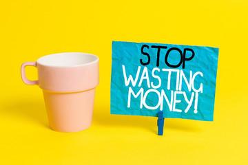 Handwriting text Stop Wasting Money. Conceptual photo advicing demonstrating or group to start saving and use it wisely Cup empty paper blue clothespin rectangle shaped reminder yellow office