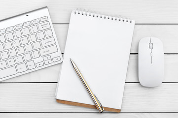 Blank notepad with computer keyboard and mouse on wooden table. Top view.