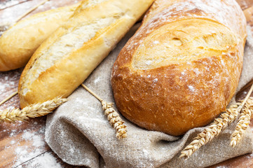 Fresh bread with wheat ears on the table. Close up.