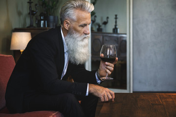 Handsome bearded senior man drinking red wine