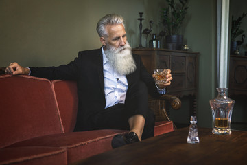 Handsome bearded senior man drinking whiskey
