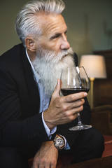 Handsome bearded senior man drinking red wine