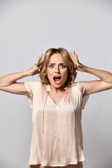 Fototapeta premium Image of excited screaming shocked beautiful woman standing isolated over light background.