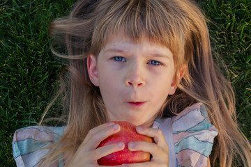 Naklejka premium Little girl with tasty apple outdoors