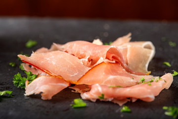 Thin sliced smoked pork ham on a dark slate