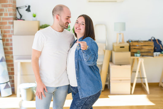 Young couple smiling very happy showing keys of new home, moving and buying new apartmet concept