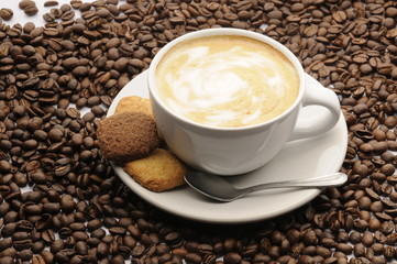 Taza de café con galletas y granos esparcidos