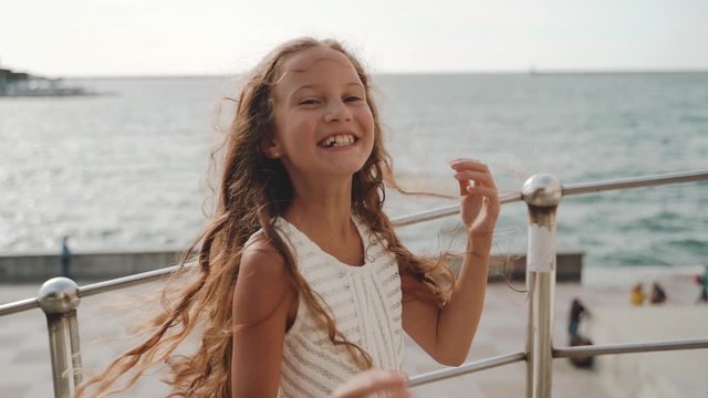 Child girl with long hair laughing near sea