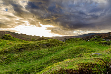 Grand swirling clouds before sunset over rolling green grass cut short by sheep near the Royal Castle of Tarbert in Argyll and Bute Scotland United Kingdom