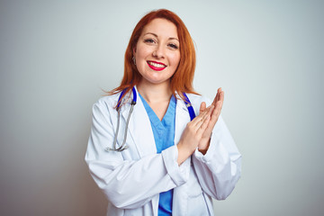 Young redhead doctor woman using stethoscope over white isolated background clapping and applauding happy and joyful, smiling proud hands together
