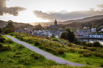 A path leads from right to left diagonally with the town of Tarbert leading to the horizon in Argyll and Bute Scotland United Kingdom