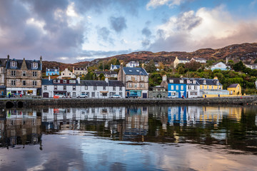 Fototapeta na wymiar Still water of Tarbert Harbour reflect the beautifully painted houses on Barmore Rd in Argyll and Bute Scotland United Kingdom