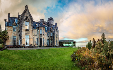 Stonefield Castle at sunset with bright green lawn in the front and some small bushes on the right in Argyll and Bute Scotland United Kingdom