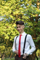 Stylishly dressed young man posing in a park. Looks surprised to the side.
