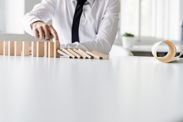 Business crisis manager stopping dominos from collapsing