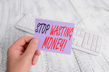 Text sign showing Stop Wasting Money. Business photo showcasing advicing demonstrating or group to start saving and use it wisely man holding colorful reminder square shaped paper white keyboard wood