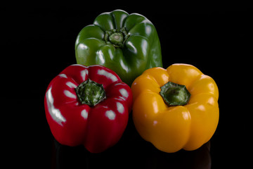 Fresh green, yellow and red peppers, top view, isolated on a black background. healthy food