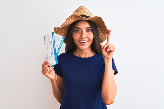 Young beautiful tourist woman holding boarding pass ticket over isolated white background surprised with an idea or question pointing finger with happy face, number one