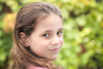Fototapeta premium Close up Portrait of 8 Years Old Girl, with Brown Long Hair and Big Brown Eyes, Happy Child, Green Background 