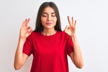Obraz na płótnie Canvas Young beautiful woman wearing red casual t-shirt standing over isolated white background relax and smiling with eyes closed doing meditation gesture with fingers. Yoga concept.
