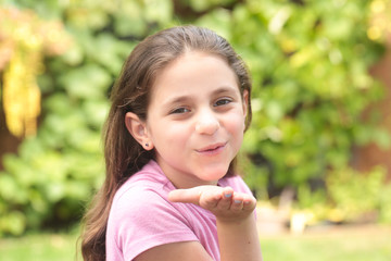 Close up Portrait of 8 Years Old Girl, with Brown Long Hair and Big Brown Eyes, Happy Child, Green Background 