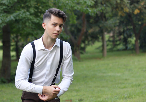 Stylishly dressed young man posing in a park. scaredly looking at the camera.