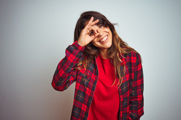 Young beautiful woman wearing red t-shirt and jacket standing over white isolated background doing ok gesture with hand smiling, eye looking through fingers with happy face.