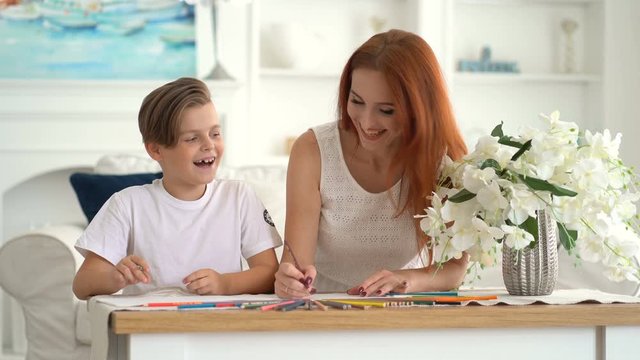 Front view - Little boy and his mother drawing and laugh at the table