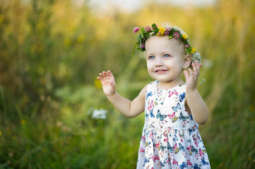 little girl with a wreath on her head and blue eyes smiles