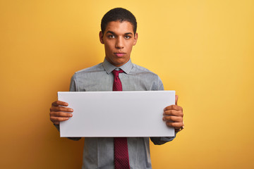 Young handsome arab businessman holding banner standing over isolated yellow background with a...