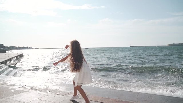 Young girl dancing near sea at summer day