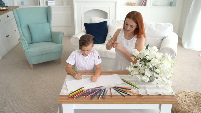 Beautiful young mother with son drawing on paper portrait View from above